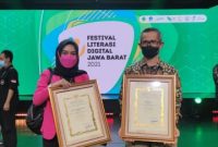 Kepala Diskominfo Garut, Muksin, bersama Kepala Bidang IKP Diskominfo Garut, Yeni Yunita, menerima secara simbolis penghargaan pada acara VIRAL 2021 yang digelar di Saung Angklung Udjo, Kota Bandung, Selasa (21/12/2021). (Foto : Diskominfo Garut).