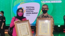 Kepala Diskominfo Garut, Muksin, bersama Kepala Bidang IKP Diskominfo Garut, Yeni Yunita, menerima secara simbolis penghargaan pada acara VIRAL 2021 yang digelar di Saung Angklung Udjo, Kota Bandung, Selasa (21/12/2021). (Foto : Diskominfo Garut).