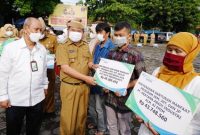 Bupati Garut, Rudy Gunawan di damping Oleh Kepala BPJS Ketenagakerjaan Cabang Garut, Widya Satriyanto, menyerahkan Santunan Jamiinan Kematiak, saat Apel Gabungan terbatas di Lapangan Setda Garut, Senin (13/12/2021)..