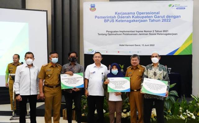 SERAHKAN. BPJS Ketenagakerjaan Cabang Garut meneyrahkan santunan Jaminan Kematian (JKM) kepada tiga ahli waris, dalam Kegiatan Kerja Sama Operasional antara Pemkab Garut dengan BPJS Ketenagakerjaan, di Ballroom Hotel Harmoni, Jalan Cipanas Baru, Kecamatan Tarogong Kaler, Kabupaten Garut, Senin (13/6/2022).