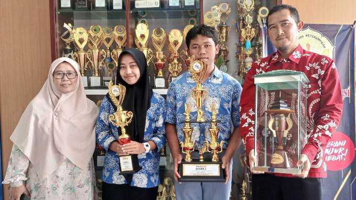 BANGGA. Aleandro dan Gina Nurul Azkiya Siswa MAN Garut yang menjuarai Supenova 4.0 Olimpiade Kimia ingkat Provinsi Jawa Barat menunjukan Piala didampingi Waka KesiswaanHendra Iskandar, s.pd, M.Pmat dan Guru Pembimbing di MAN 1 Garut, Rabu (22/2/2023)