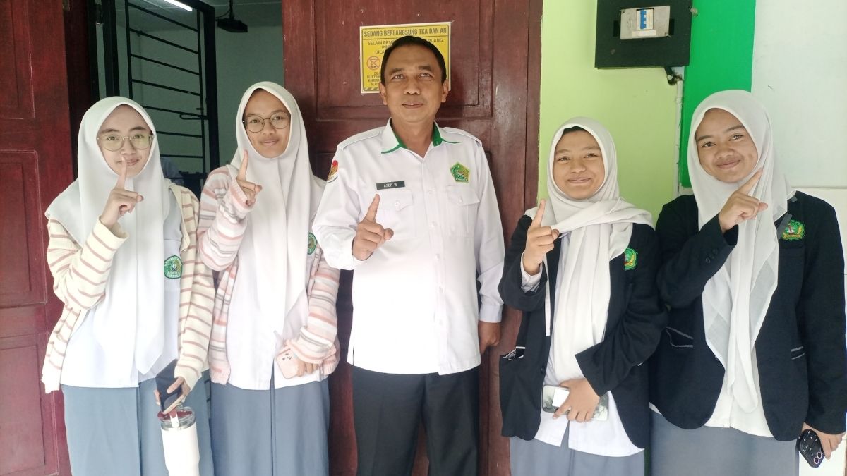 Plt Kepala MAN 1 Garut berfoto bersama siswi usai melaksanakan Tes Kemampuan Akademik (TKA) di ruang komputer MAN 1 Garut, Jalan Jend. Ahmad Yani Koropeak, Suci, Kecamatan Karangpawitan, Kabupaten Garut, Selasa (27/10/2026).